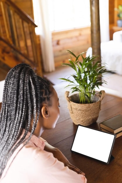 A person smiling while working on a tablet in a bright, plant-filled apartment, with a cat sitting beside them. The tablet screen shows a project management app with tasks being completed. Casual and relaxed atmosphere.