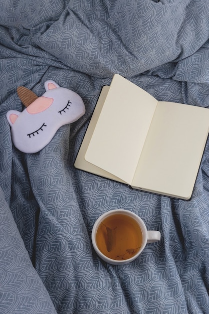 An open book or notebook, with a pen, lying on a bedside table next to a sleeping person, representing good sleep habits.