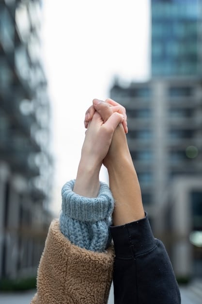A close-up of two hands clasped together, symbolizing trust and support between two people. The background is blurred to keep the focus on the hands.
