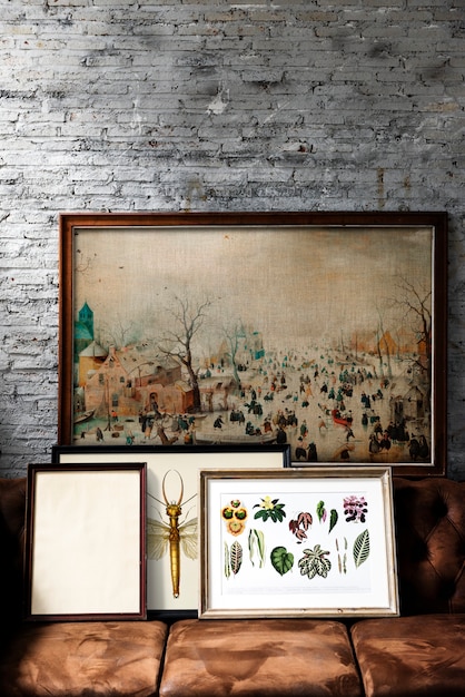 A close-up shot of a gallery wall featuring a mix of framed artwork and repurposed thrift store items. A vintage mirror, a decorative plate, and a small wooden sculpture are interspersed among the framed pieces, adding texture and visual interest to the display.