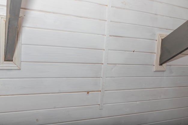 Close-up shot of a partially installed shiplap wall. showing the details of the planks, the spacing between them, and the fasteners used. The image captures the do-it-yourself aspect of the project.