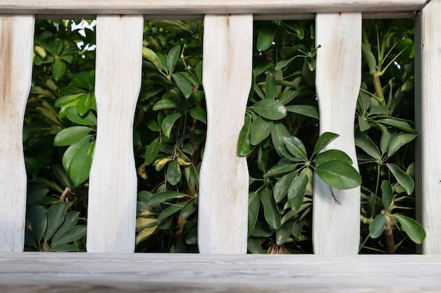 A close-up of a DIY privacy screen made from repurposed wood pallets, showing the textured wood grain and various heights of the pallet boards. The background is blurred, but shows a green garden.